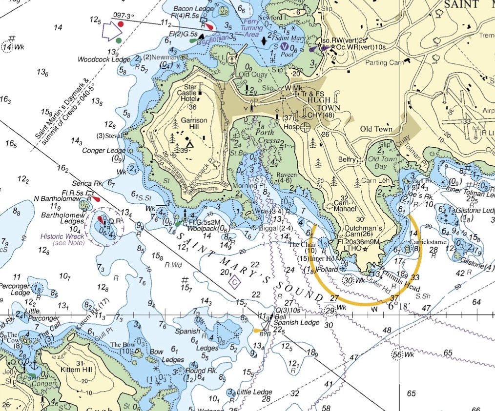 Southern approach to St. Mary’s in the Scillies - this is the route taken by larger vessels, including the ferry, at low water The route is marked by a a series of solid and dashed lines. An east cardnal ‘Spanish Ledge’ marks the shallows of Spanish Ledges to the west - large vessels will keep east of this buoy. Further to the northwest, a green post (‘Woolpack’) and a red post and buoy (‘N Bartholomew’) mark the edges of a narrow channel with rocks either side. Sea kayakers might choose to avoid large vessels by keeping out of this channel. To the north east, two more lateral marks (including ‘Bacon Ledge’) mark the narrow channel into Hugh Town harbor. Note the arrow with green and red spots printed just north of Woodcock Ledge on the map. This indicates the ‘direction of buoyage’ - i.e. which side of the channel has red marks and which has green marks.